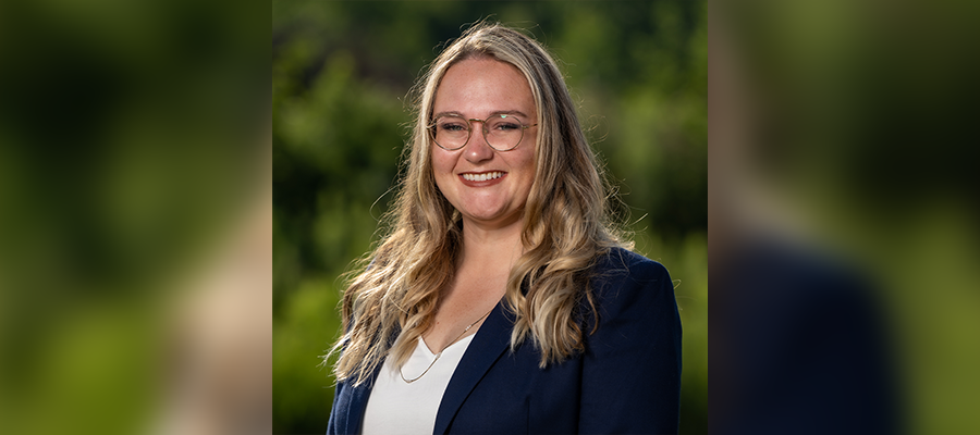 Anna Davis, Operations Manager at ACRT Services, wearing glasses, a navy blazer, and white top, smiling outdoors with greenery in the background.
