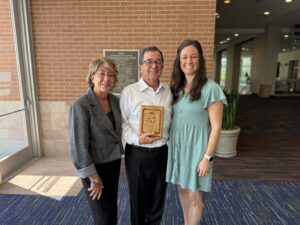 Rich Hendler stands with his family, proudly holding the UAA Lifetime Achievement Award at the 2025 Trees & Utilities Conference.